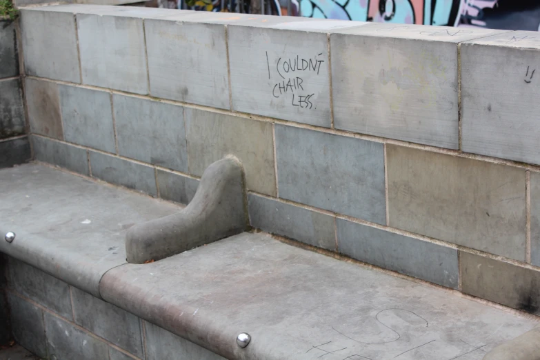 cement bench with graffiti painted on it by a wall