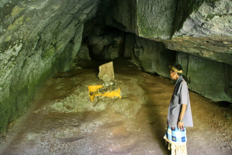 a woman standing inside a cave with a rock wall