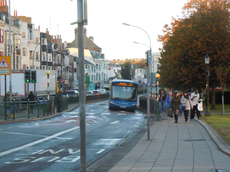 people wait at a bus stop as a commuter bus passes