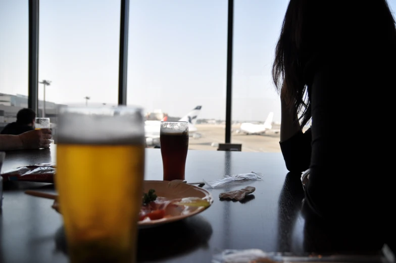 a table with a plate and a glass on it and a person at the table with drinks in front of it