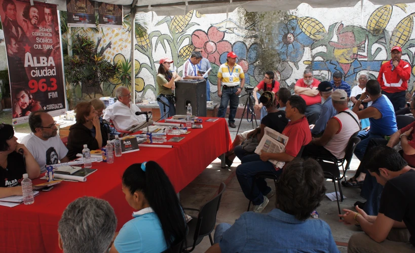 several people are gathered around a table with book and magazines on it