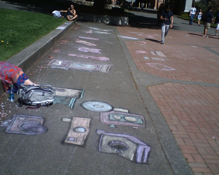 chalk drawings on a sidewalk with people walking