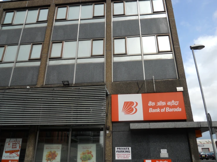 a tall grey building with an orange and white sign