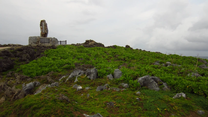 a green hillside with some rocks and a stone monument