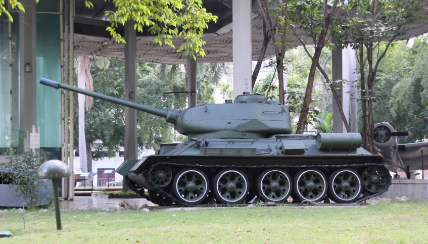 the small, camouflaged tank stands alone in front of a building