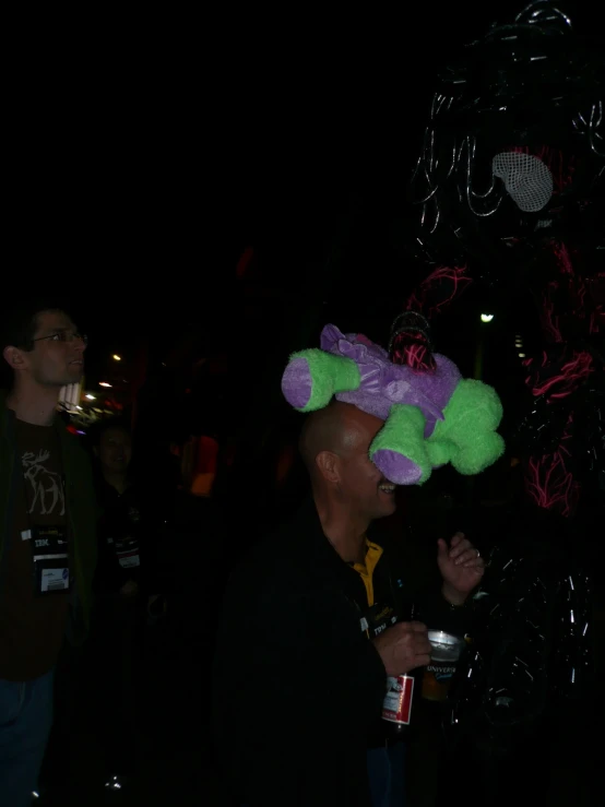 a man in black shirt standing under a purple and green balloon hat