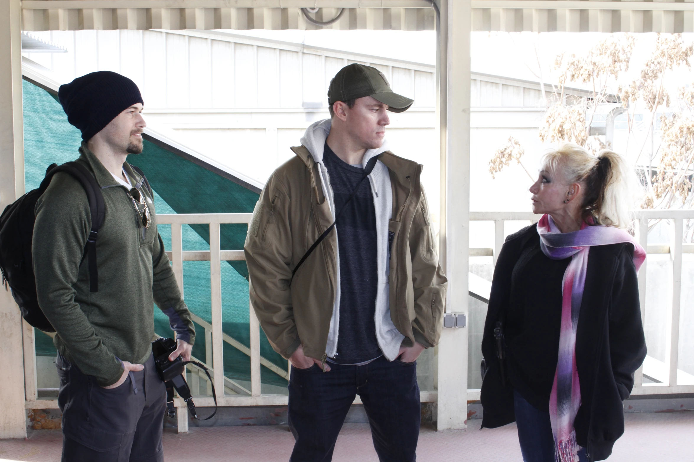 three people in winter attire standing by a wall