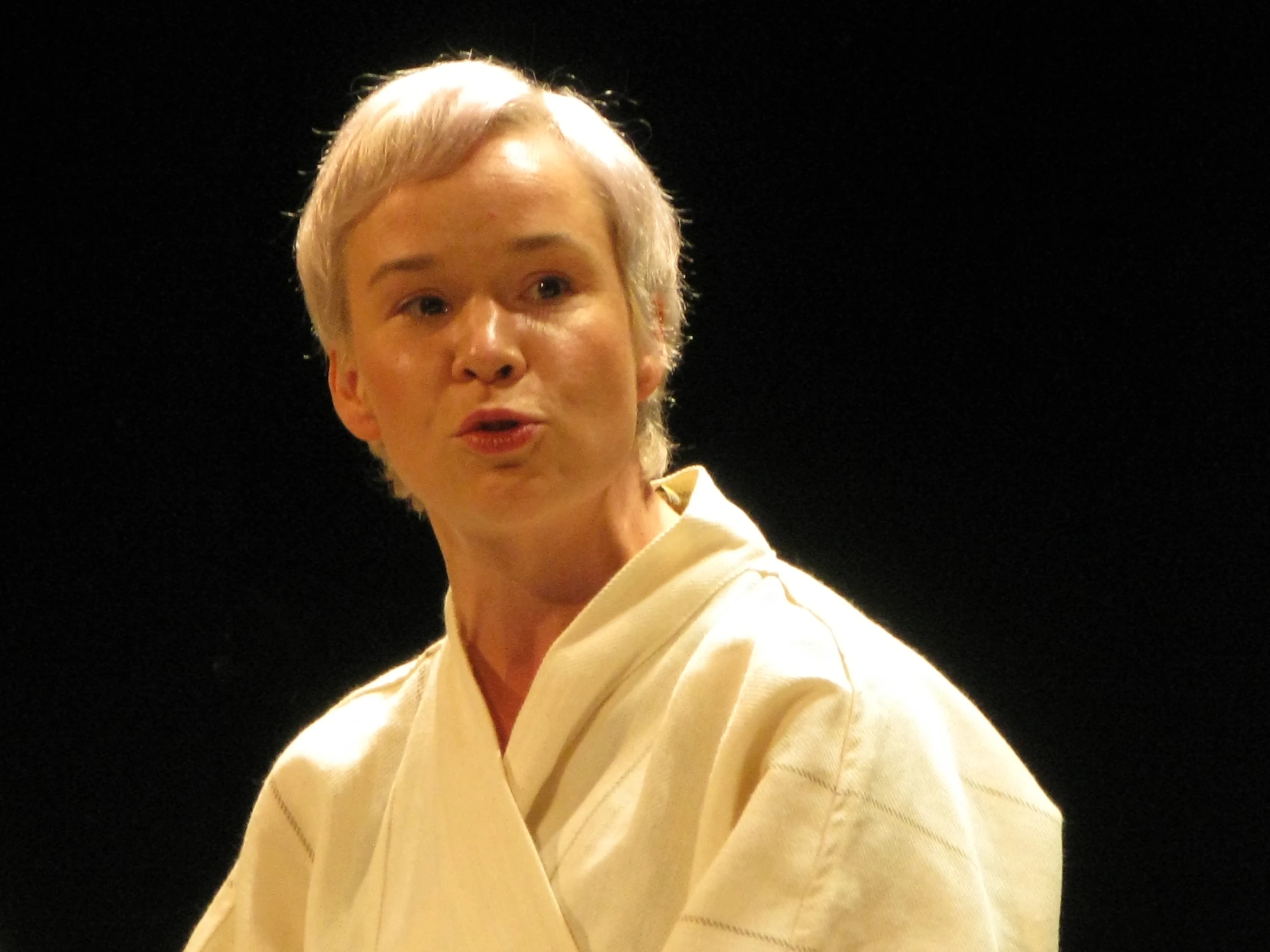 a woman standing in front of a microphone wearing a white robe