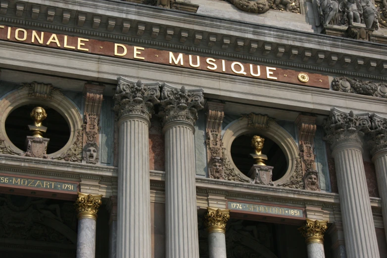 a column in front of a large building with a gold and white sign