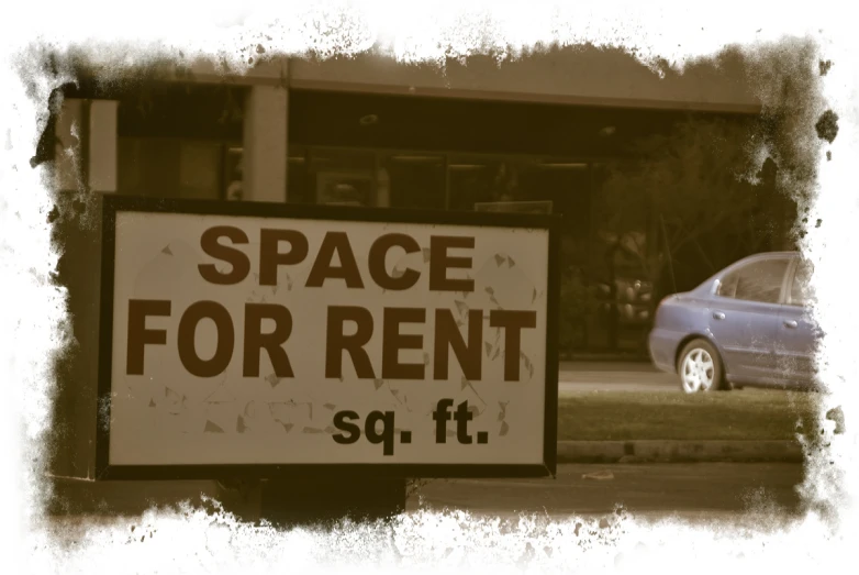 a car sits parked next to a space for rent sign