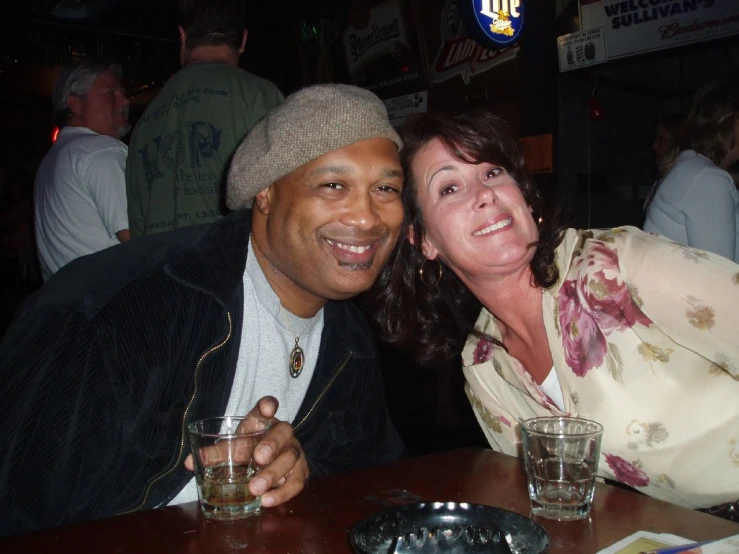 a man and woman posing for the camera in front of a bar