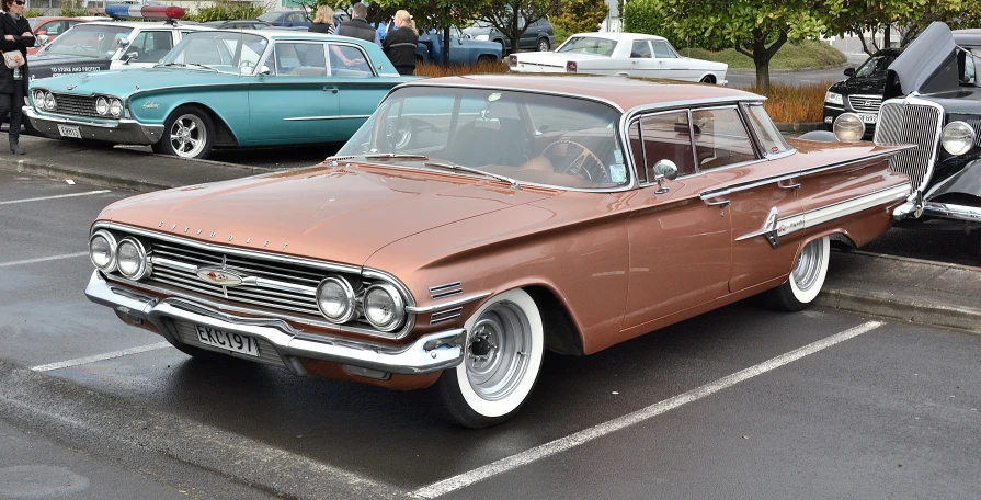 a very old fashioned, burnt orange car parked next to other cars