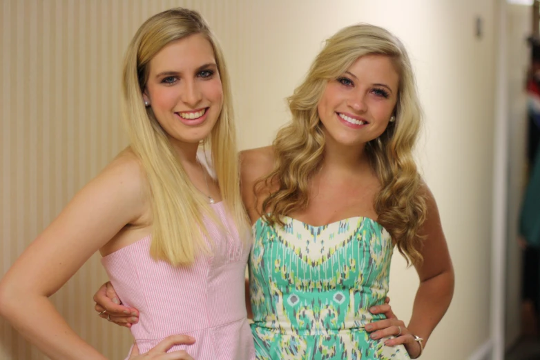 two blonde haired women in formal clothes posing for a camera