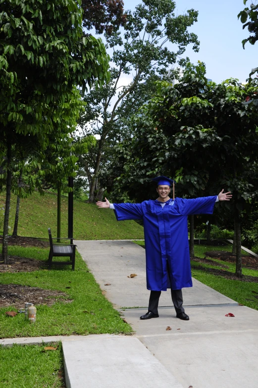a man in blue robe standing on sidewalk with his arms out