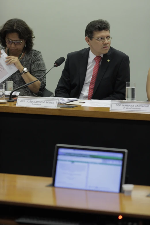 people sitting at a table with microphones and papers