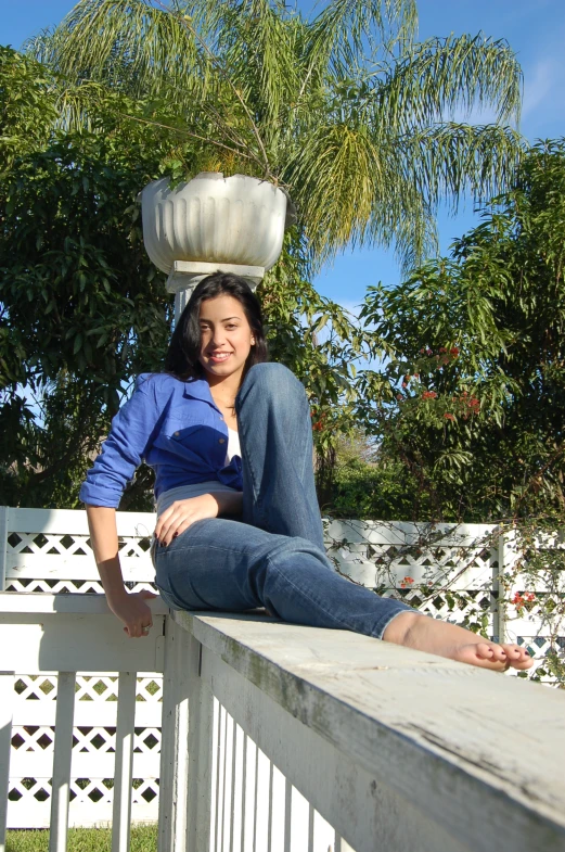 a woman sitting on top of a wooden fence