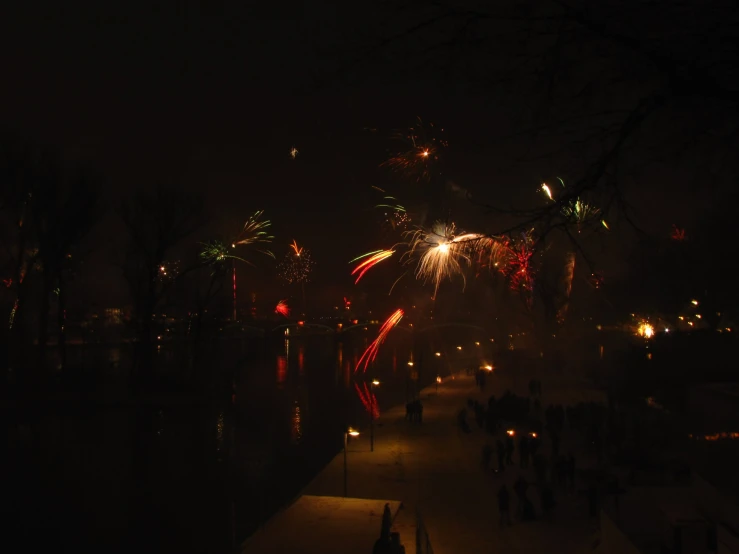 people are gathered at night watching fireworks go off