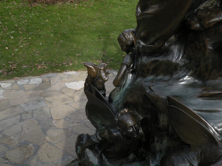 a statue sitting on top of a sidewalk next to a green field