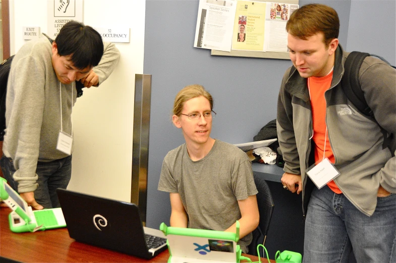 two men and one  looking at laptops