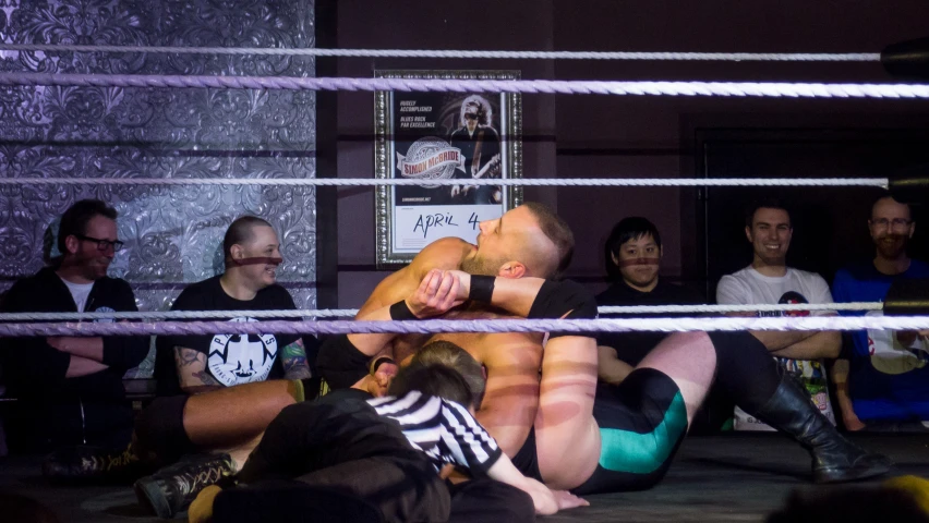 several people and two men wrestling on the ring