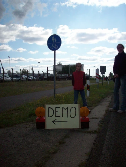 two people are standing near a road sign