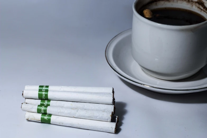 cigarettes resting on top of each other next to a cup of coffee