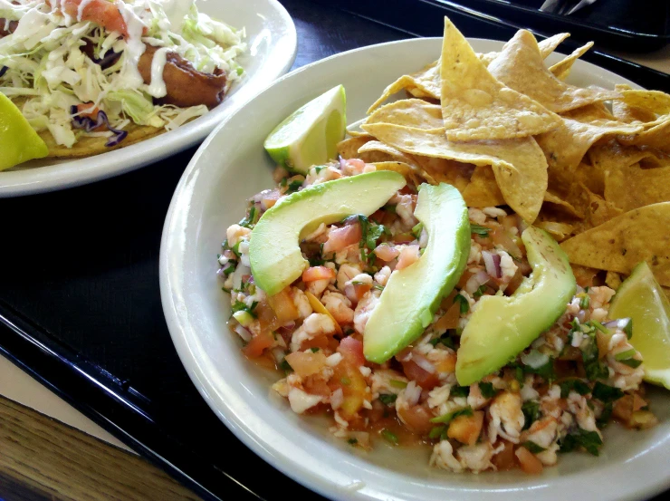 two plates with chips and food next to a salad