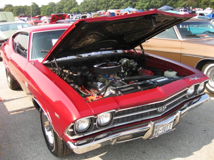 the engine compartment of a red car in a parking lot