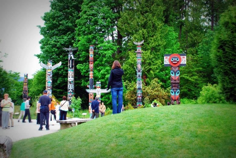 people walking by various totems in the park