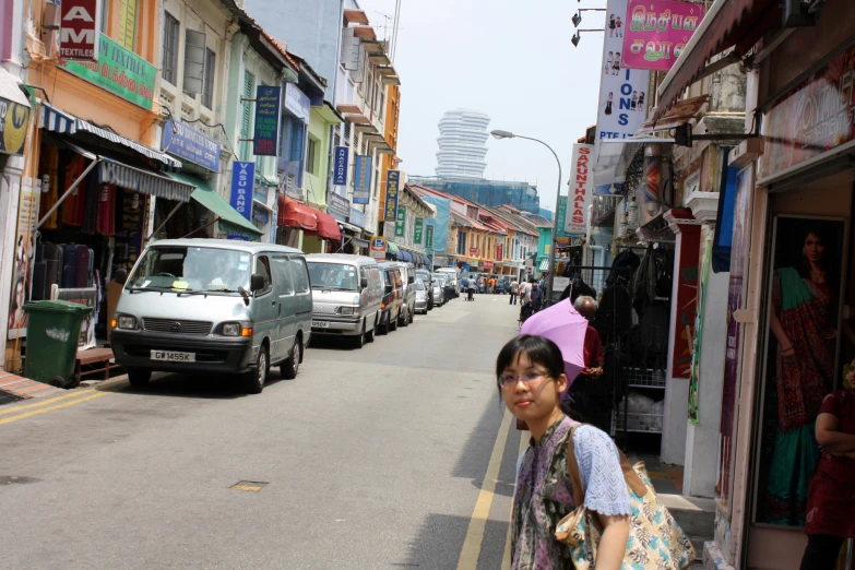 woman standing at the end of a street between several stores