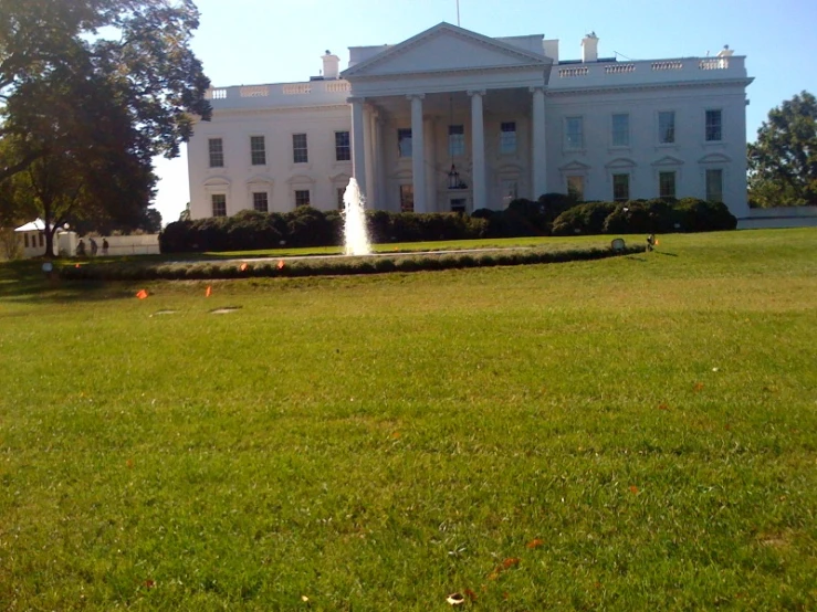 the large white house has a fountain in front of it