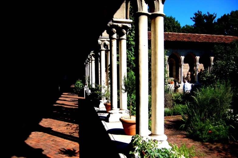 a brick walkway covered in lots of plants and stone columns