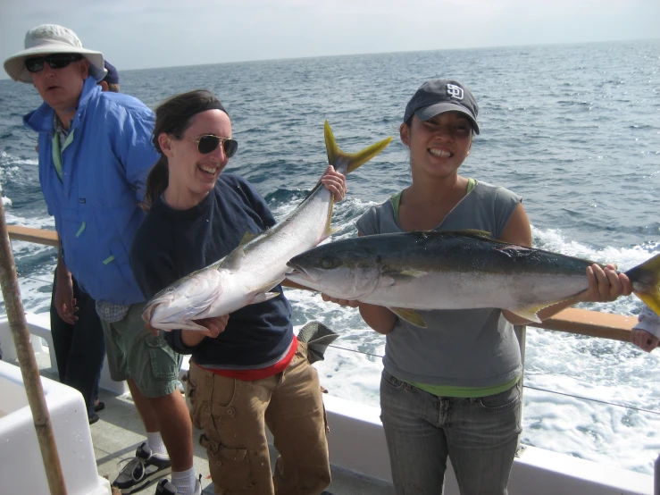 people holding up fish on a boat near the ocean