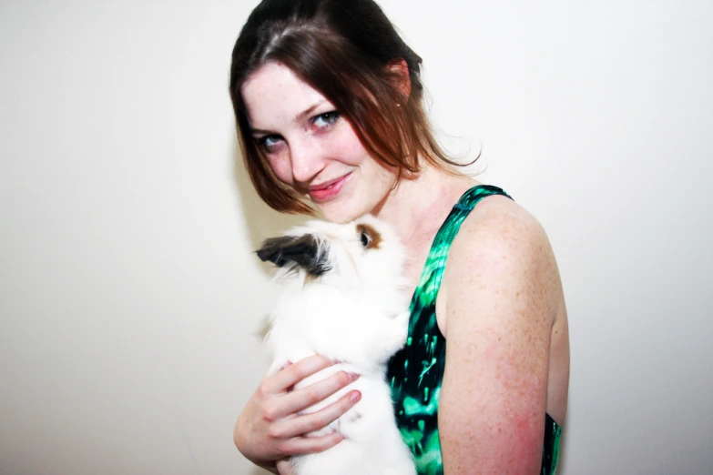 a woman is holding a small rabbit in her lap