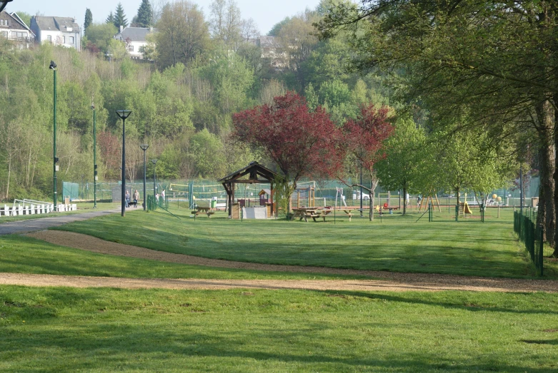 an empty park area in the shade, with several benches and a gazebo