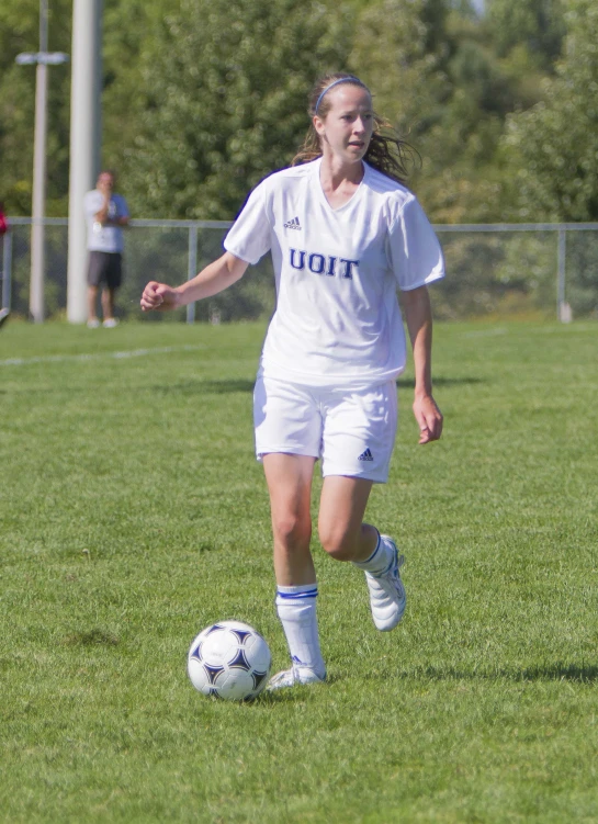 female soccer player wearing white uniform playing soccer