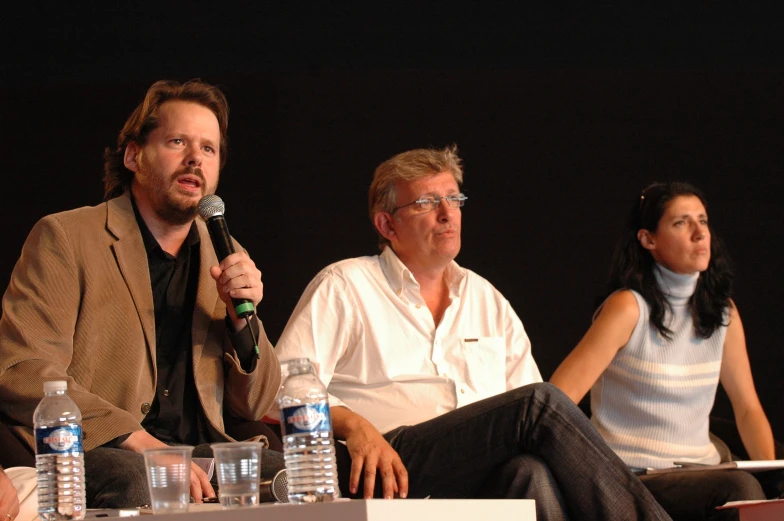 two men and a women are on stage at a panel discussion