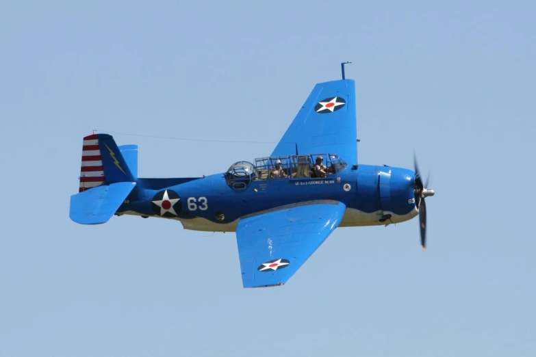 an older blue war plane is flying in the air