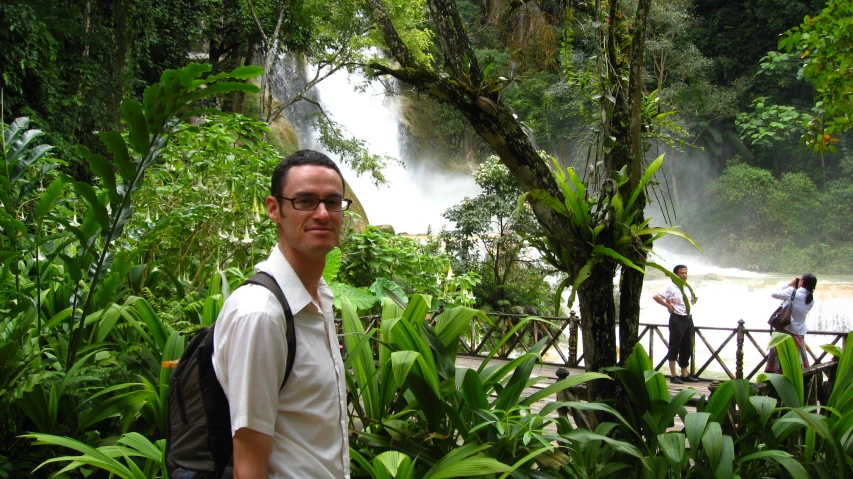 two men standing next to one another near a large waterfall