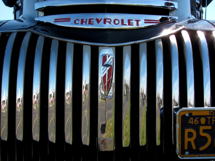 the front end of an antique car, featuring chrome lettering and a vertical grille