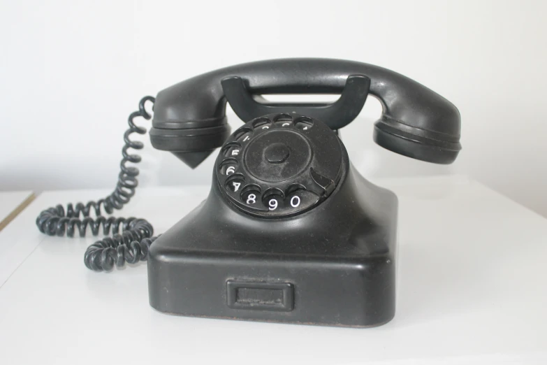 a very old fashioned black telephone on the table