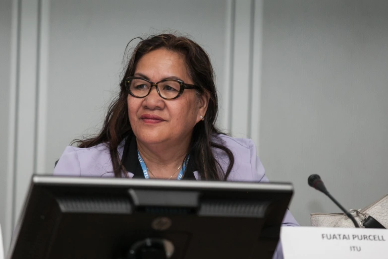 a woman is sitting at a desk with microphones