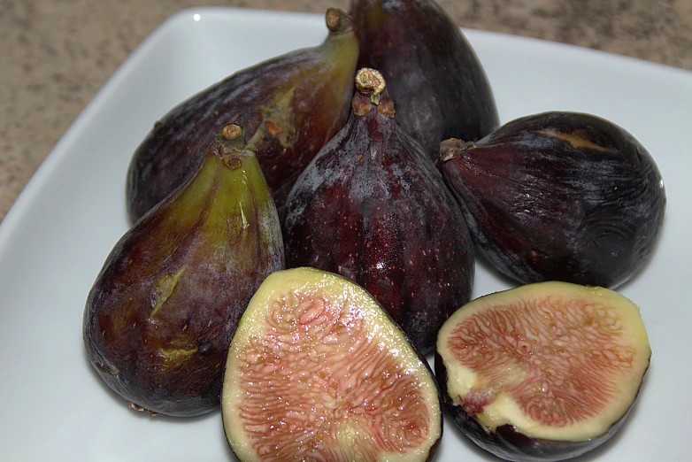 figs sitting on a square white plate and sliced