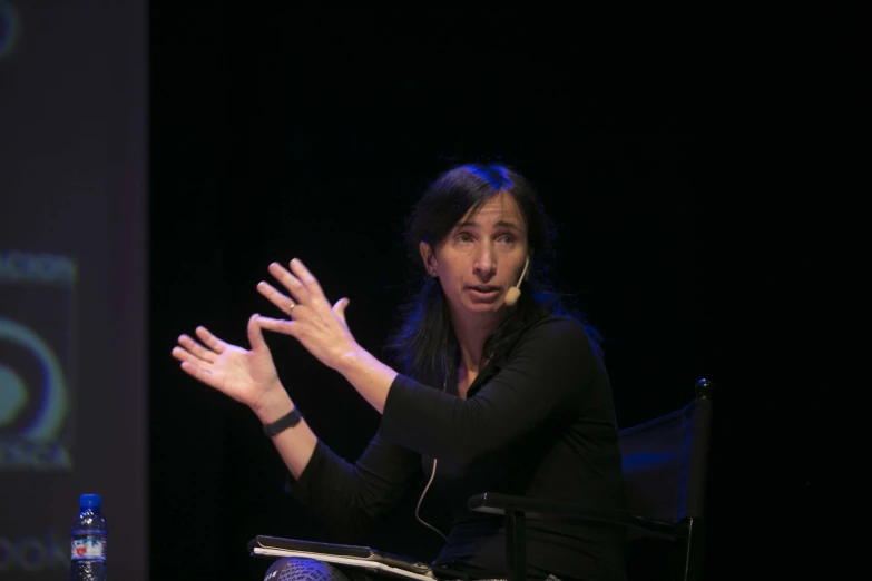 a woman sits in a chair at an event