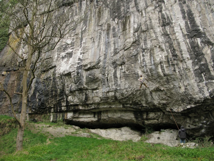 the person is standing next to the huge rock