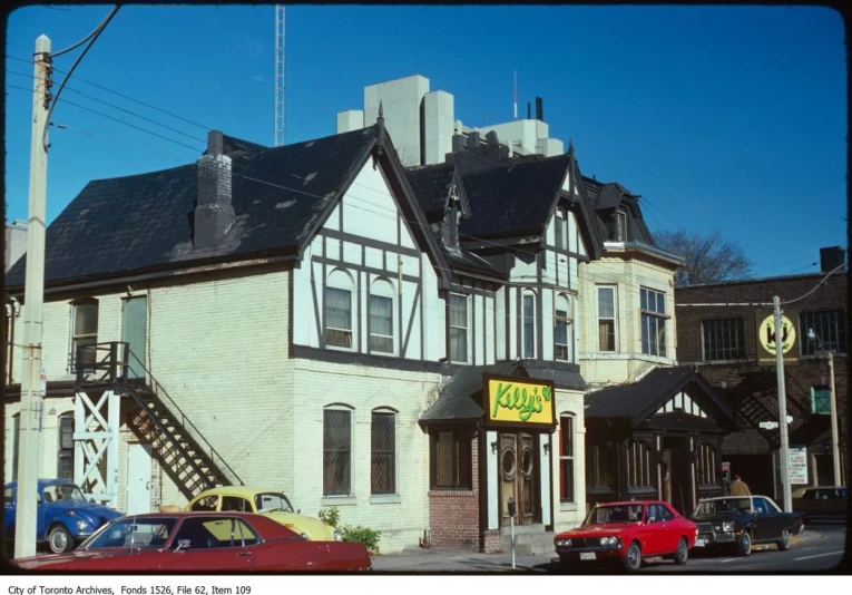 a old building has a sign and cars parked on the side