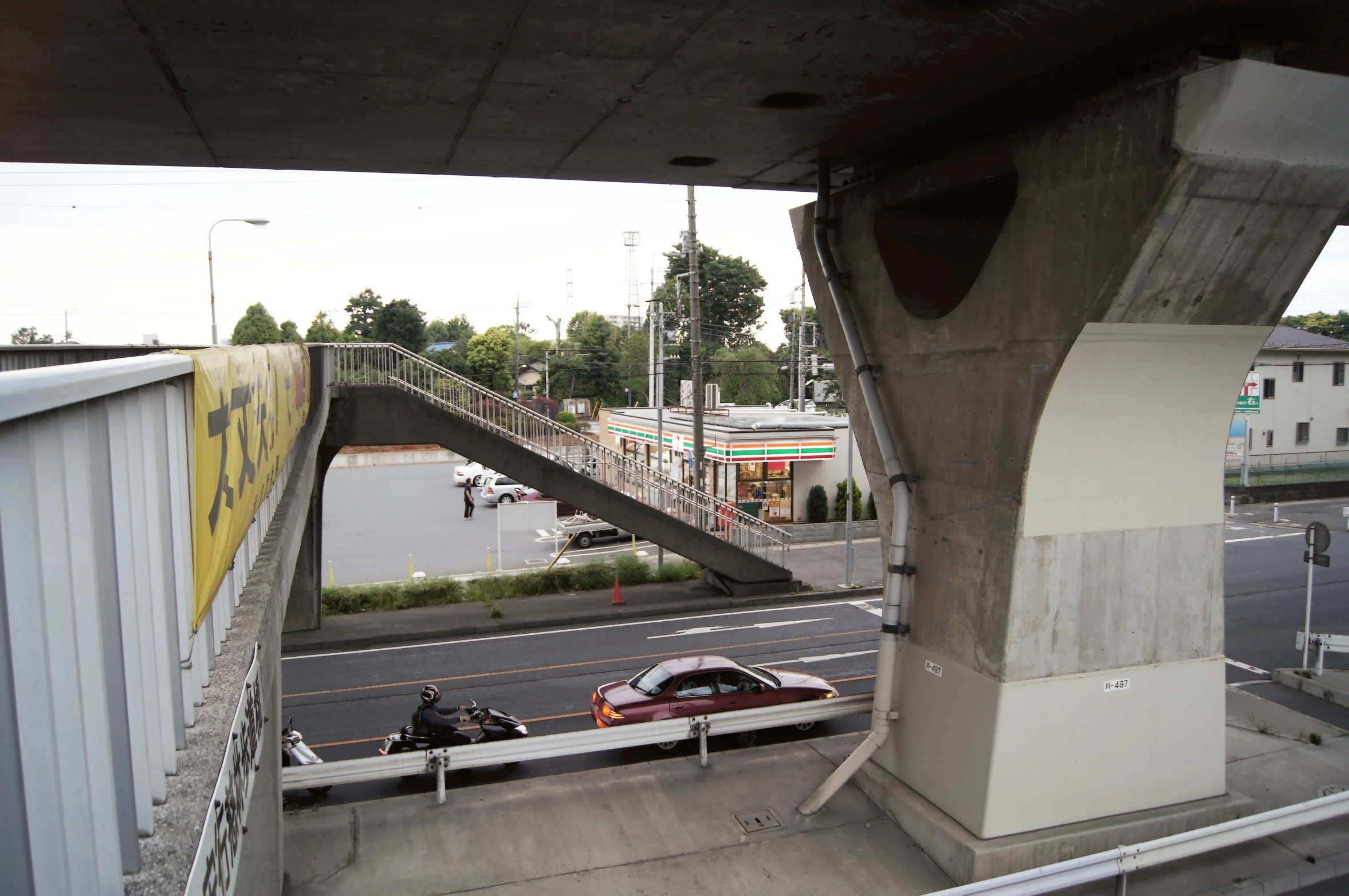 cars are driving down the road beside a bridge