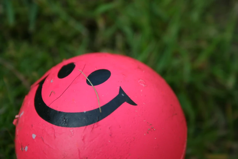 a red ball has a black smiley face on it