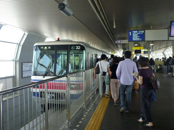 people are standing at a train station with a subway car parked on the platform