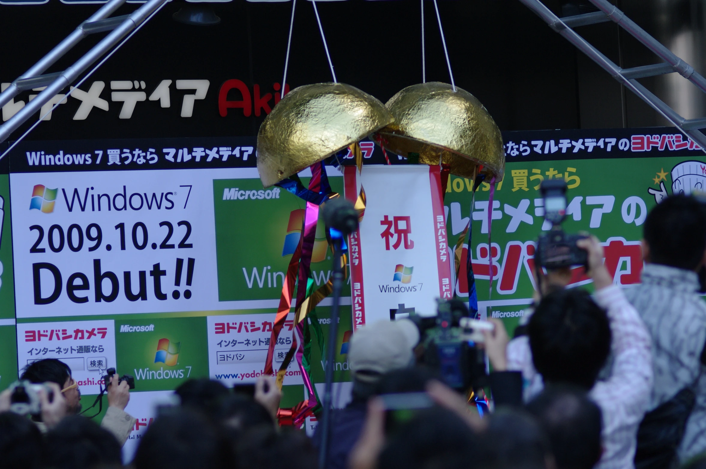 a group of people standing under a stage with balloons hanging from it